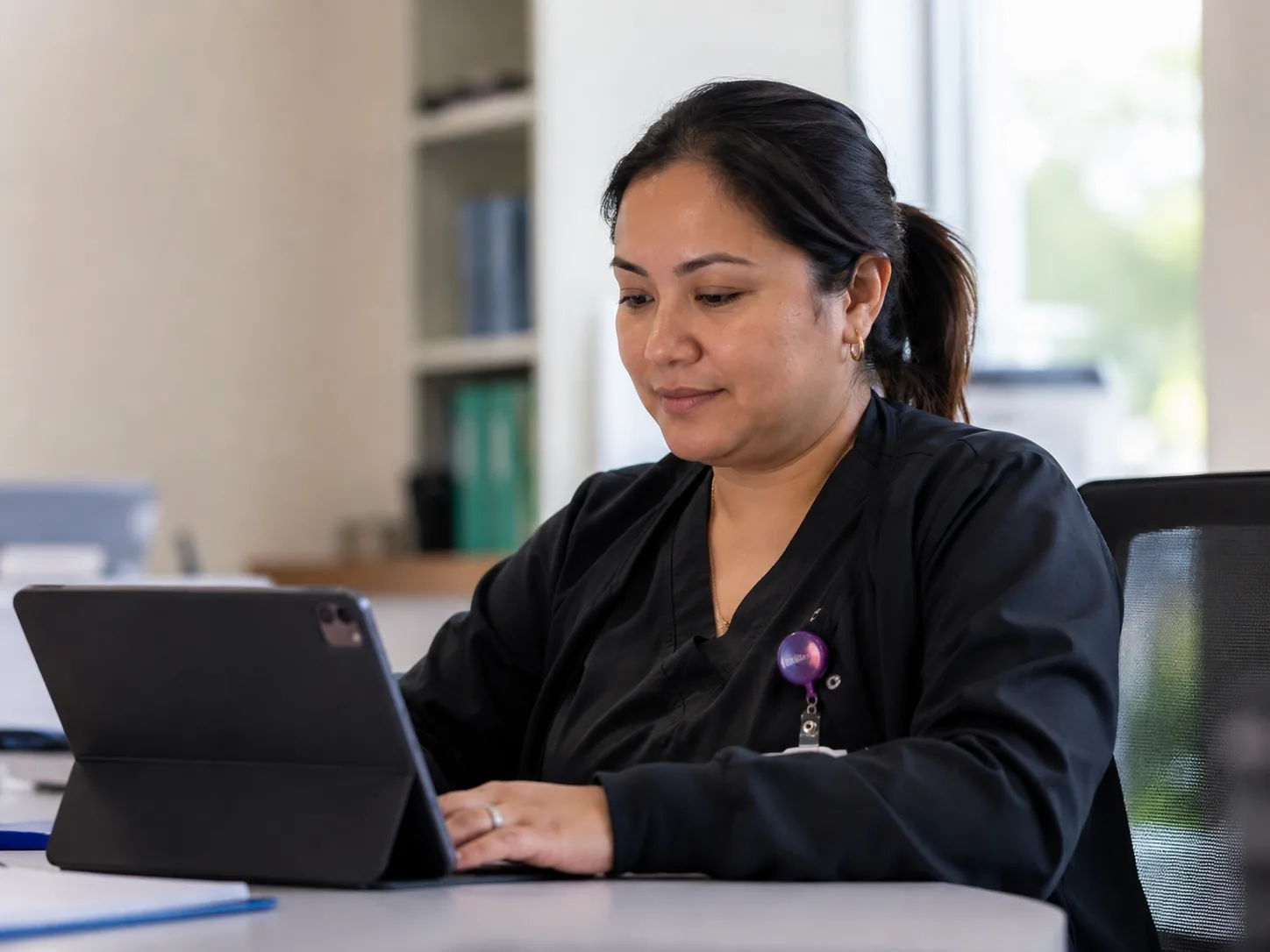 Healthcare professional in scrubs working on a tablet