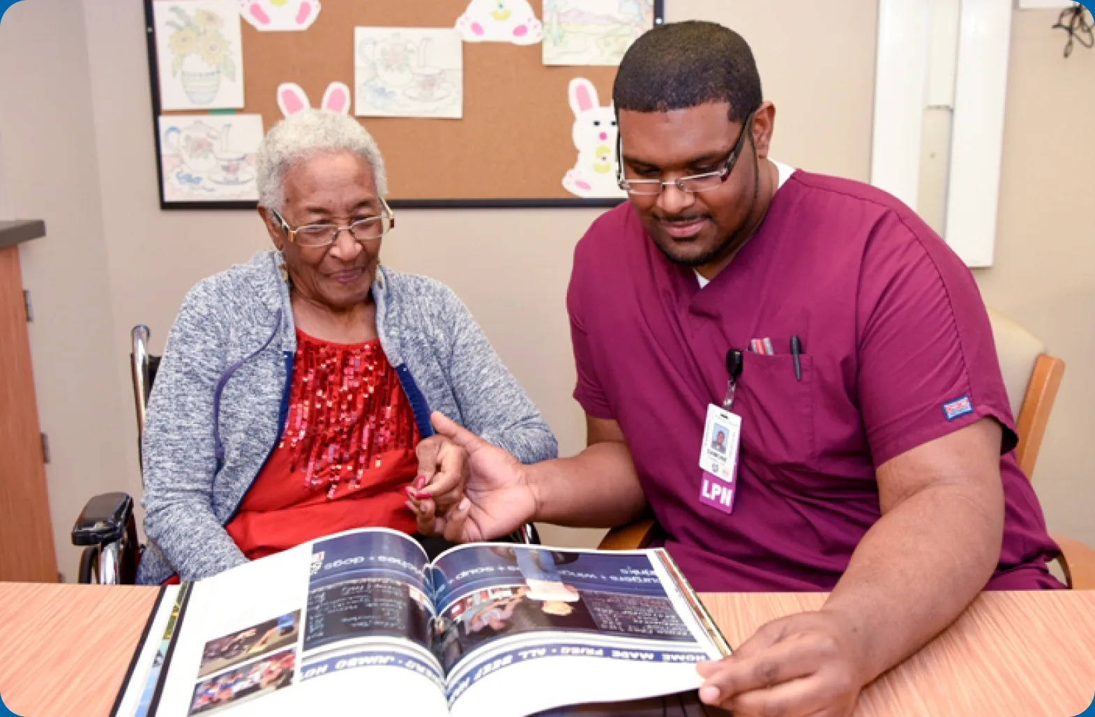A Kaleida Health nurse sits with a patient, looking through a photo book together.