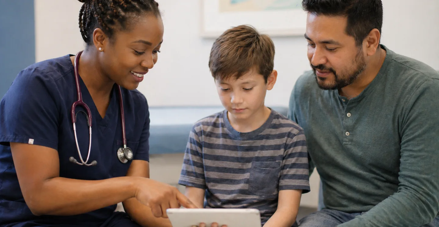 Pediatric nurse reviewing care with a young patient and his father at Golisano Children's Hospital of Buffalo